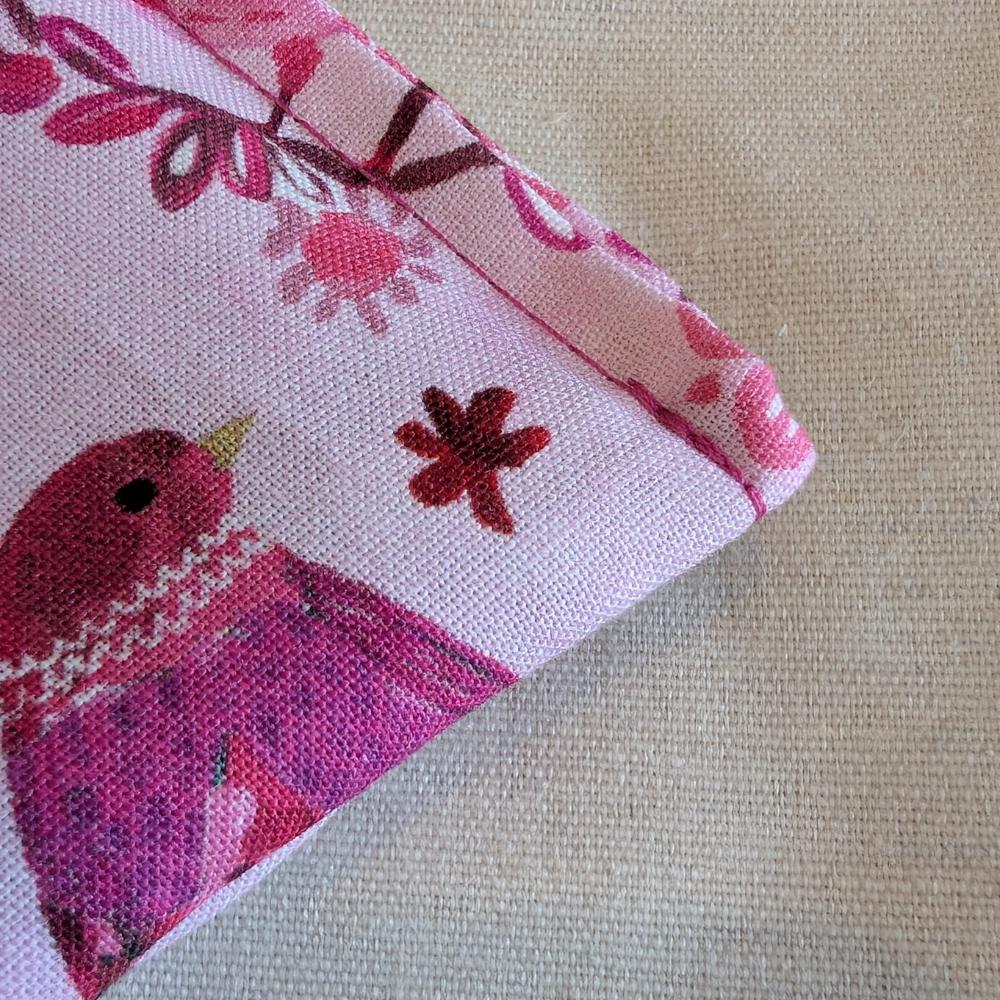 Fabric with a pink bird and floral pattern on a beige background