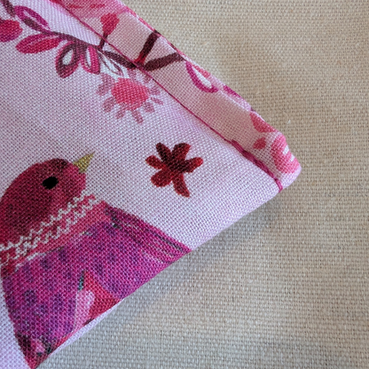 Fabric with a pink bird and floral pattern on a beige background