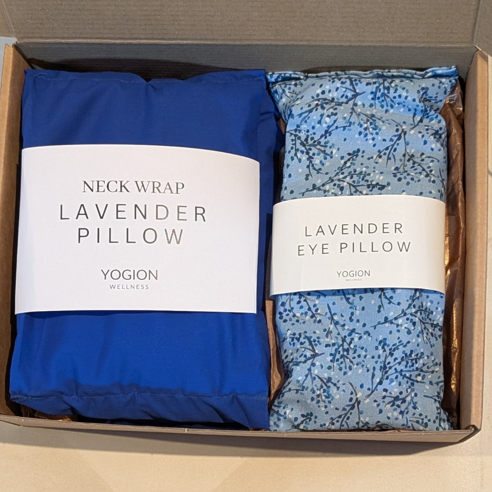 Two lavender pillows, one blue neck wrap and one eye pillow with floral pattern, in a box labeled 'Yogion Wellness'.