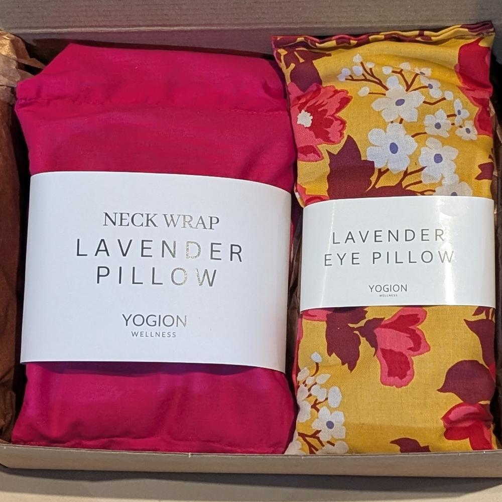 Two lavender products, a pink neck wrap and a floral eye pillow, in packaging with visible labels.