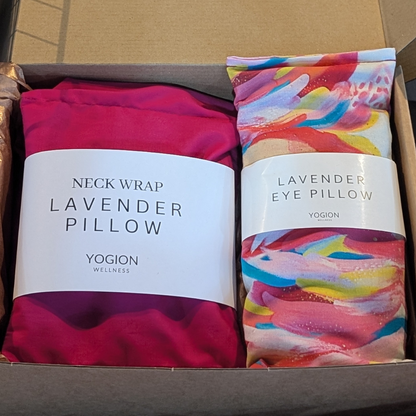 Two lavender products in a box, one pink neck wrap and one abstract paint fabric eye pillow, with labels on by yogion wellness.