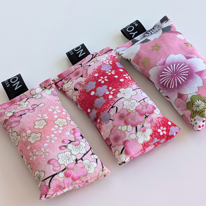 Three pink floral fabriclavender sachet bags with cherry blossom patterns on a white background by yogion wellness