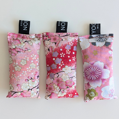 Three pink floral fabriclavender sachet bags with cherry blossom patterns on a white background by yogion wellness