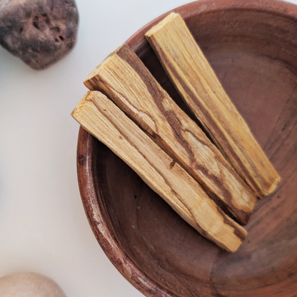three palo santo sticks in a wooden bowl 