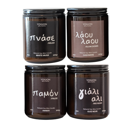 Four Yogion Melodies soy wax candles in dark amber glass jars with black lids, arranged in a 2x2 grid on a white background. The labels feature different scents in Greek: White Musk, Cashmere, Amber, and Oud Noir.