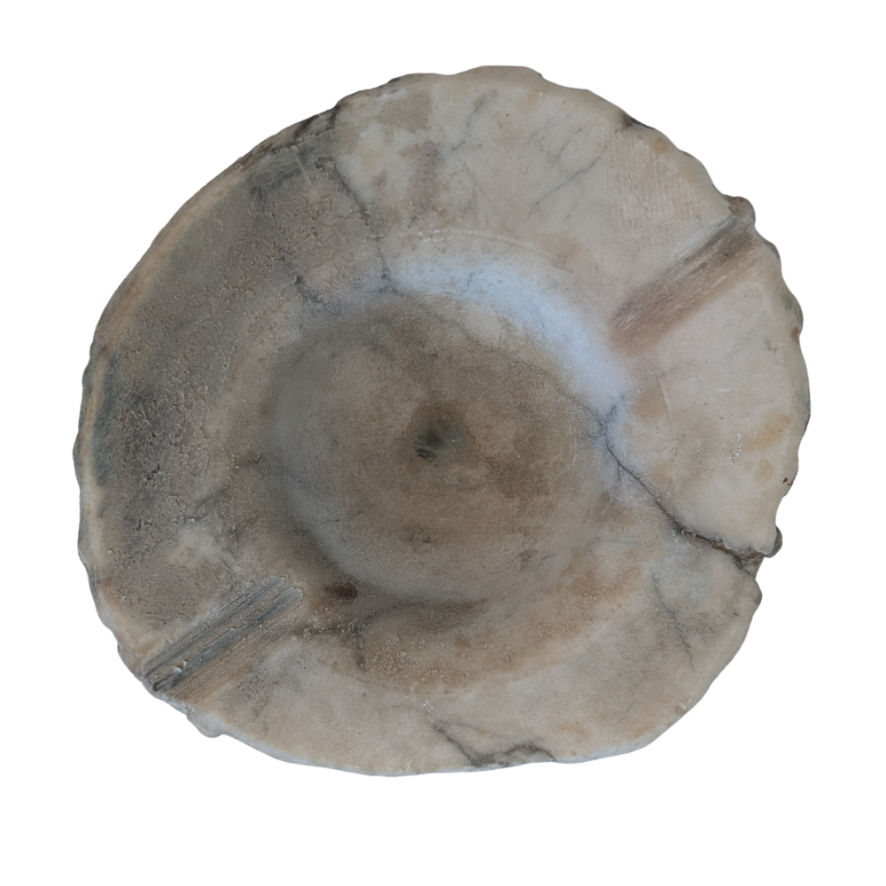 A round, handcrafted stone bowl with a scalloped edge and a textured, natural surface in shades of beige, gray, and brown, isolated on a white background.