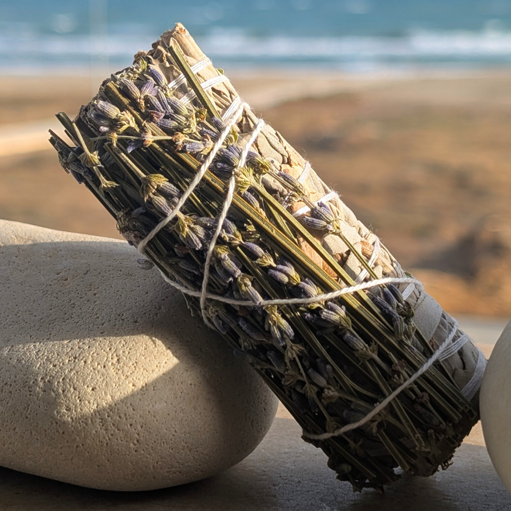 Hand-tied white sage and lavender smudge stick , rock in a beach
