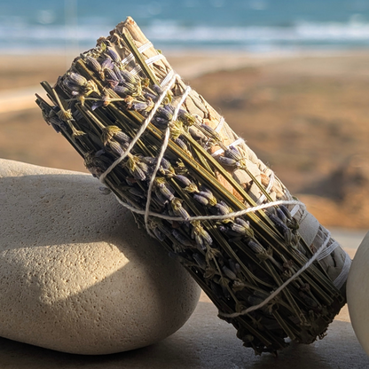 Hand-tied white sage and lavender smudge stick , rock in a beach